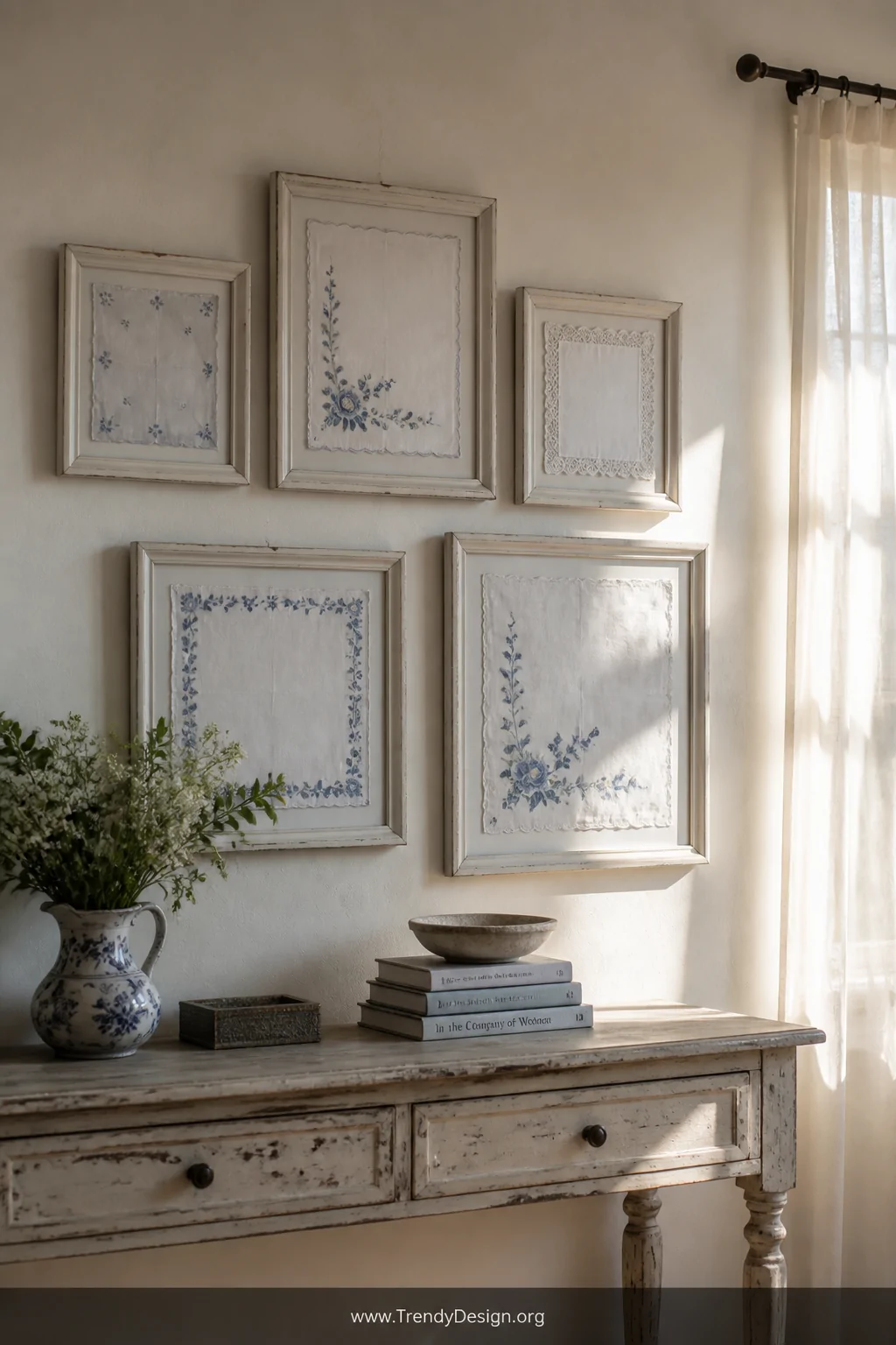 A French countryside cottage gallery wall featuring five mismatched wooden frames painted soft white, displaying stretched vi
