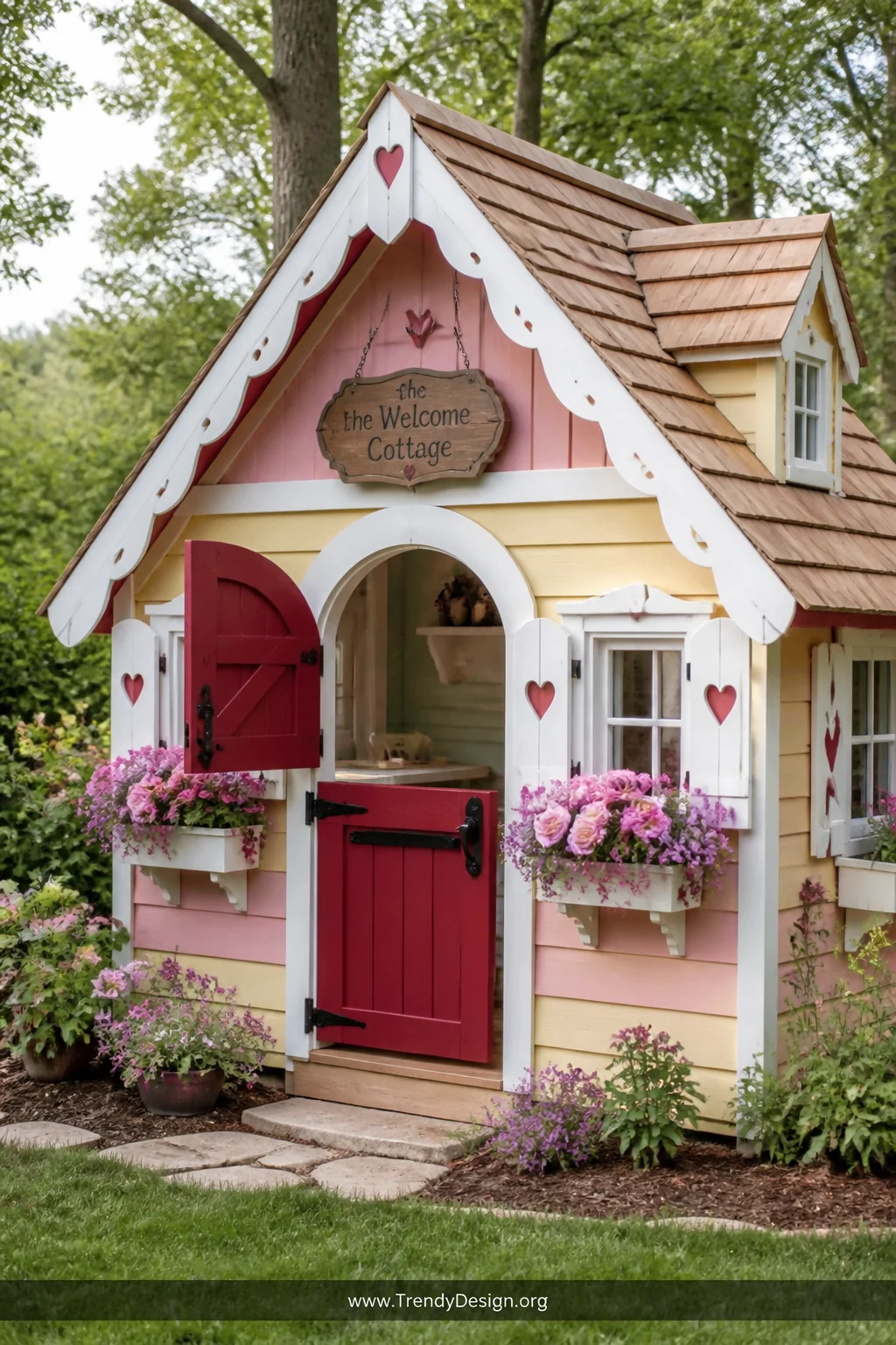 Wide exterior shot of a whimsical miniature cottage playhouse with gingerbread trim, candy-pink and butter-yellow painted wal