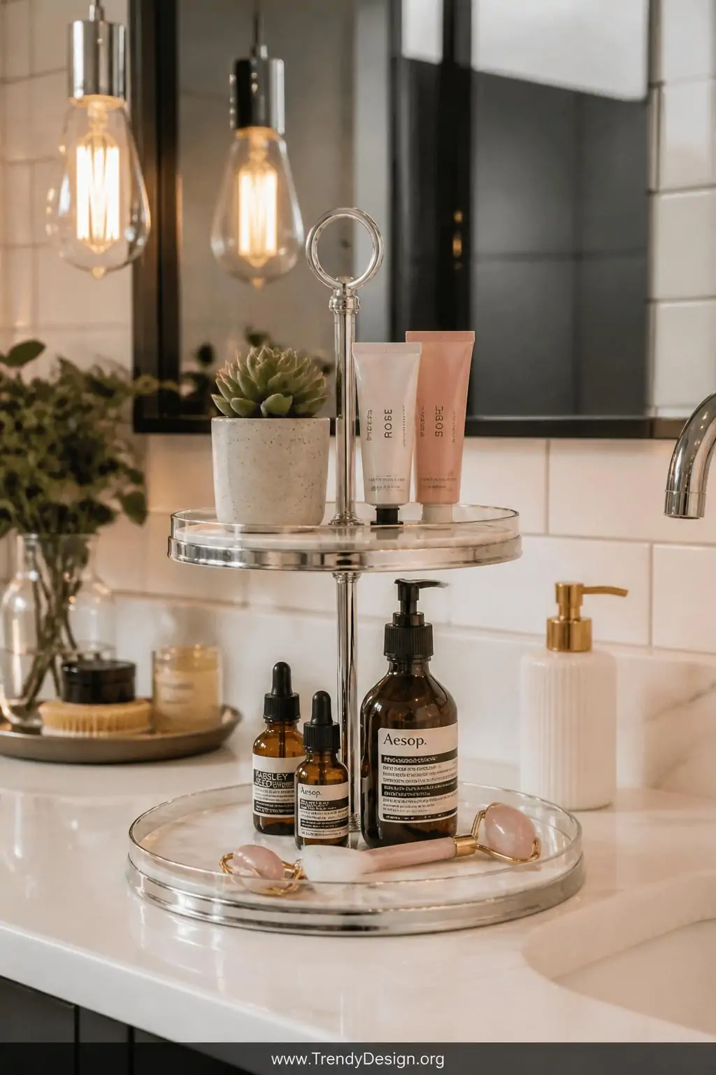 Wide shot of a marble-look tiered tray on a white quartz bathroom countertop, bottom tier holding amber glass skincare serums