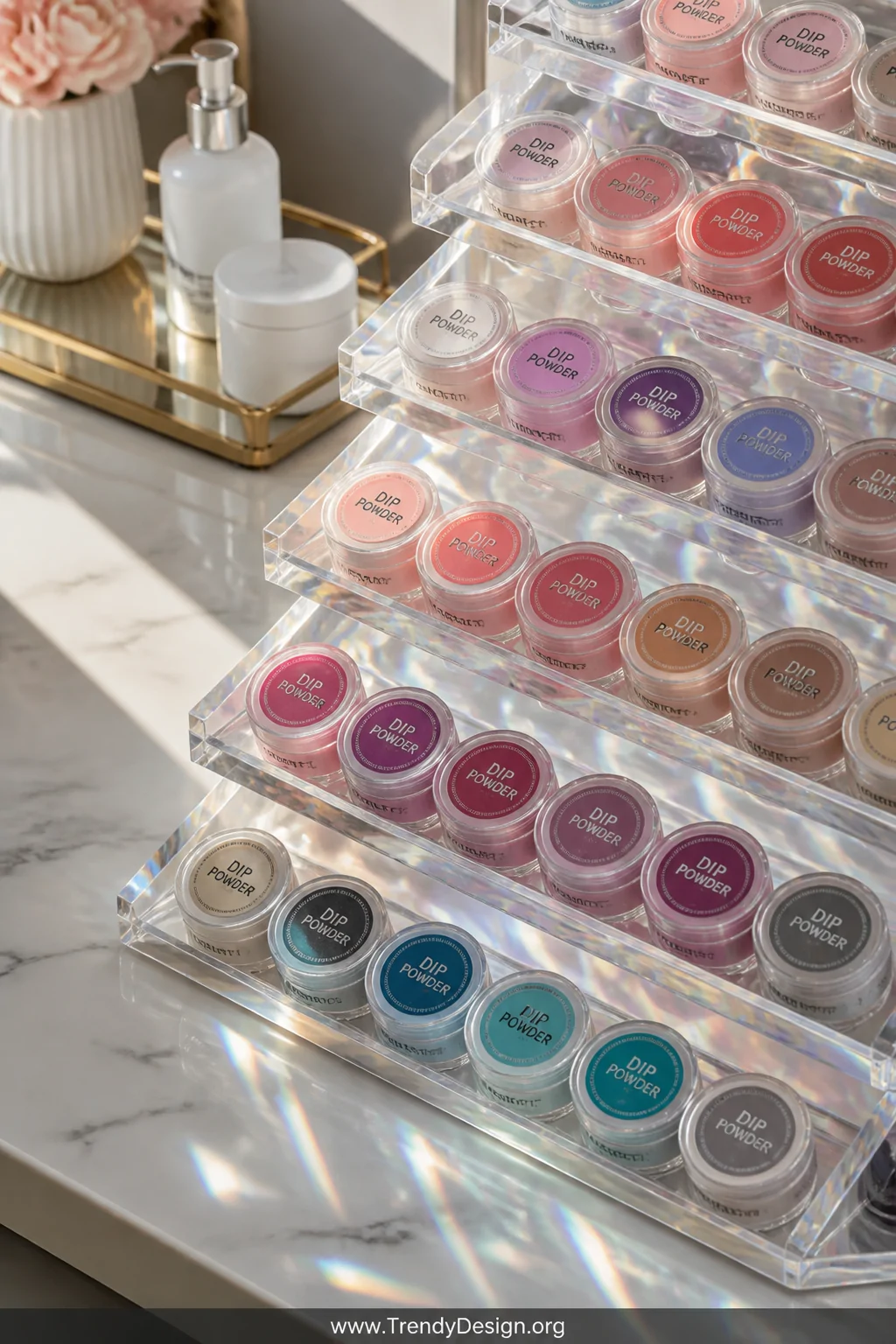 A close-up detail shot of a tiered clear acrylic organizer on a white marble vanity, filled with rows of neatly arranged dip 