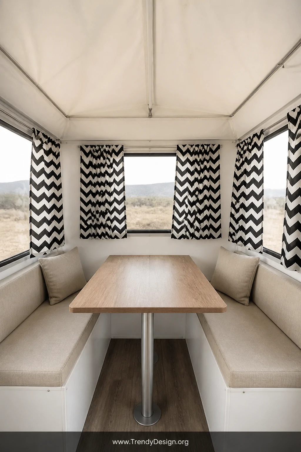 Wide interior shot of a compact pop-up camper dining nook with crisp black and white chevron patterned cotton canvas curtains
