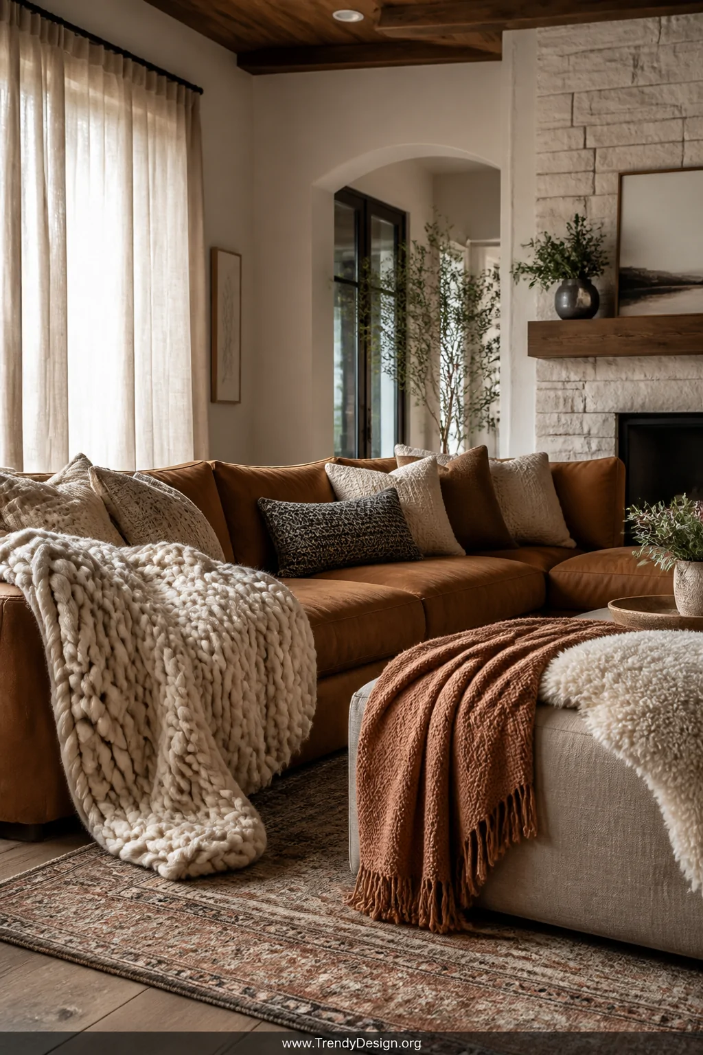 Wide-angle photorealistic interior shot of a cozy modern rustic living room sofa styled with a chunky cream knit blanket drap