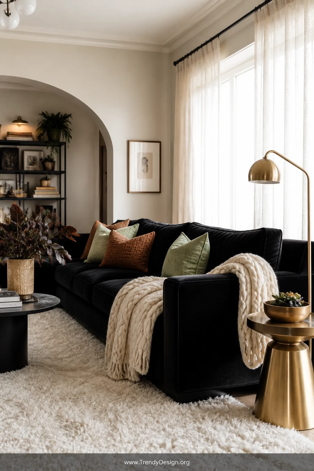 Wide-angle photorealistic interior shot of a luxurious living room anchored by a deep black velvet sofa adorned with chunky k