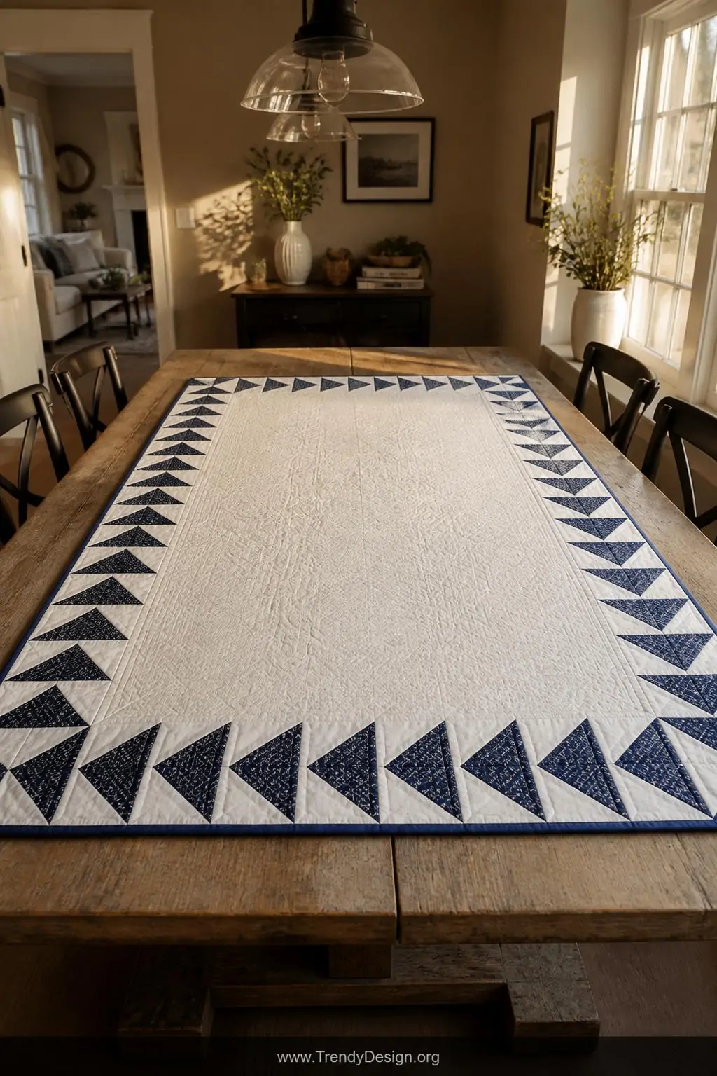 Wide shot of a finished quilt displayed flat on a weathered farmhouse dining table, featuring a single row flying geese borde