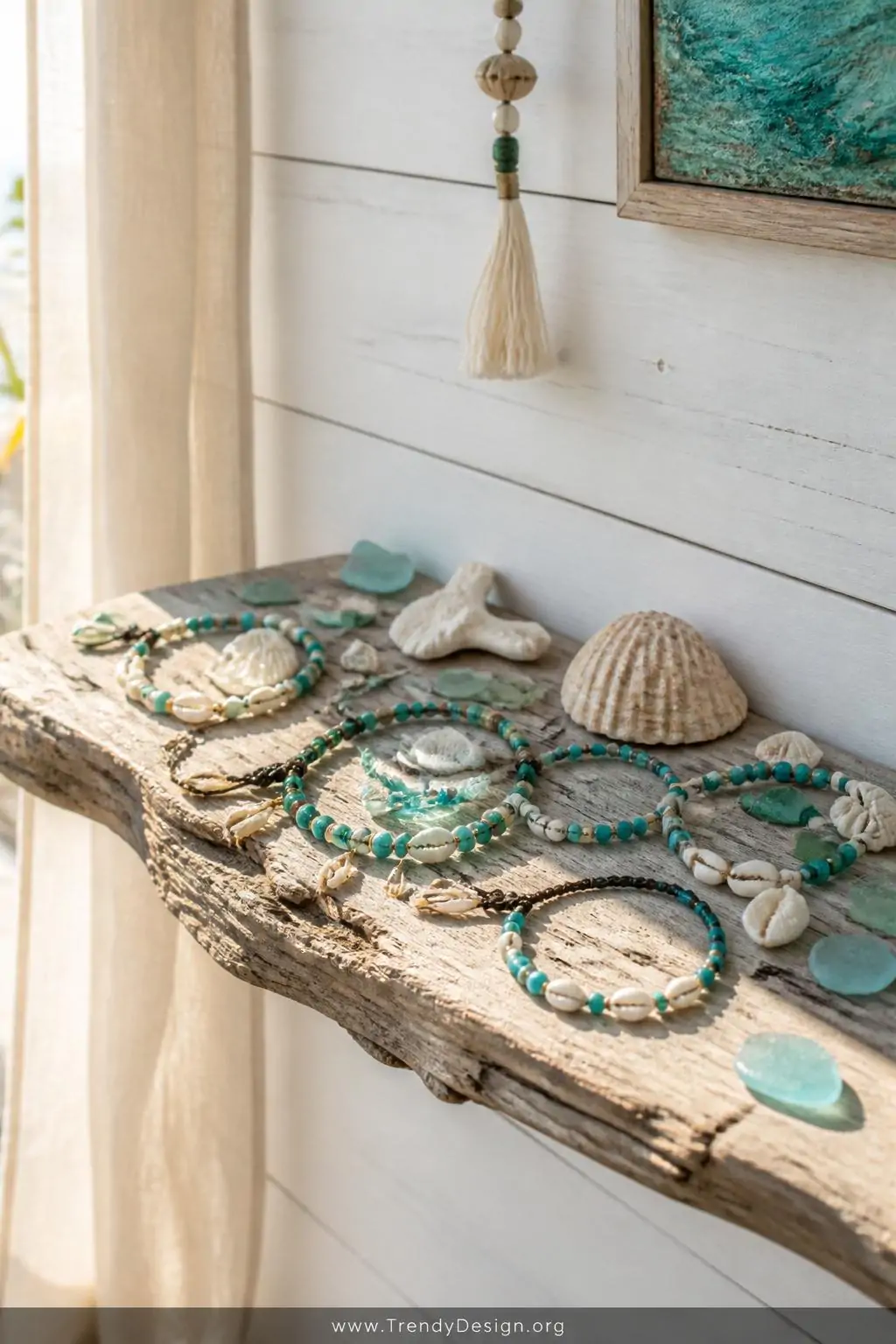 A weathered driftwood display shelf mounted against a whitewashed shiplap wall holds a collection of turquoise and cowrie she