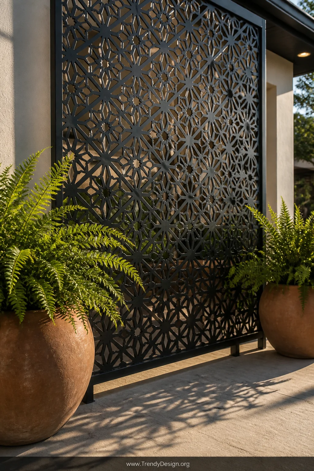 Medium shot of a sleek powder-coated black steel decorative screen panel with intricate geometric cutout pattern, modern matt