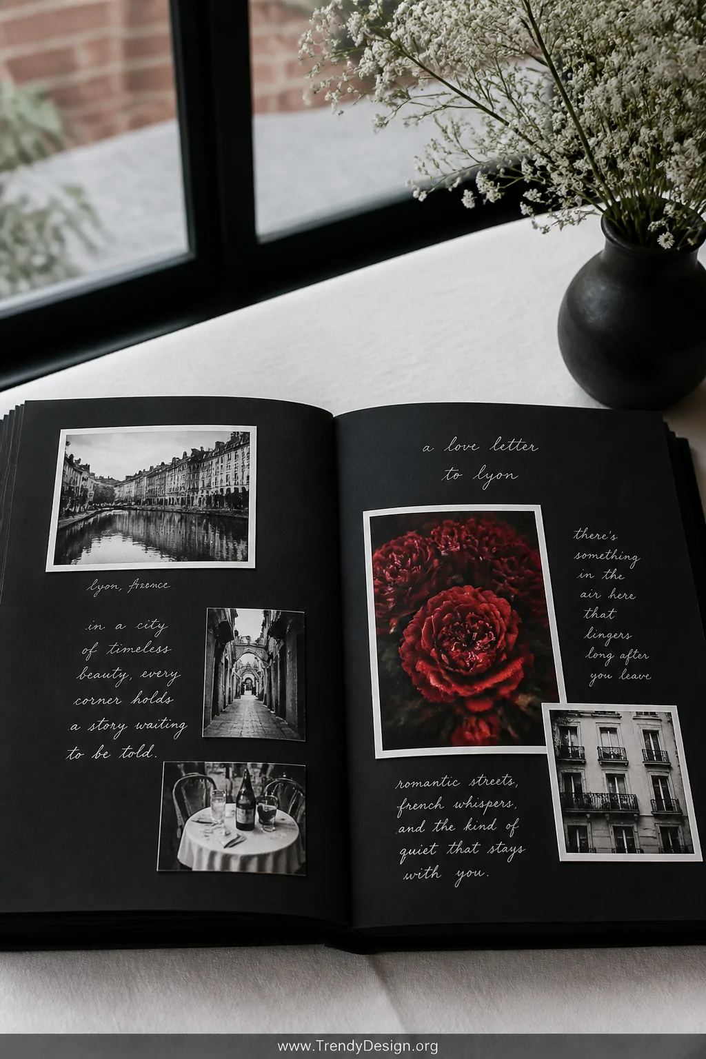 A medium-shot photorealistic styled vignette of an open black scrapbook on a white linen tablecloth under cool natural window