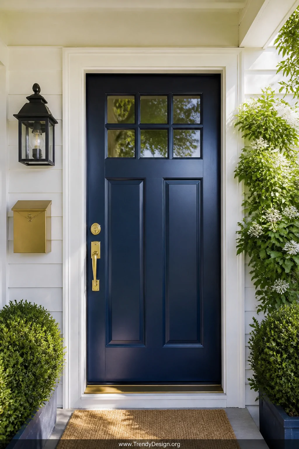 A medium-distance shot of a freshly painted deep navy blue front door gleaming in bright daylight on a small cottage-style po