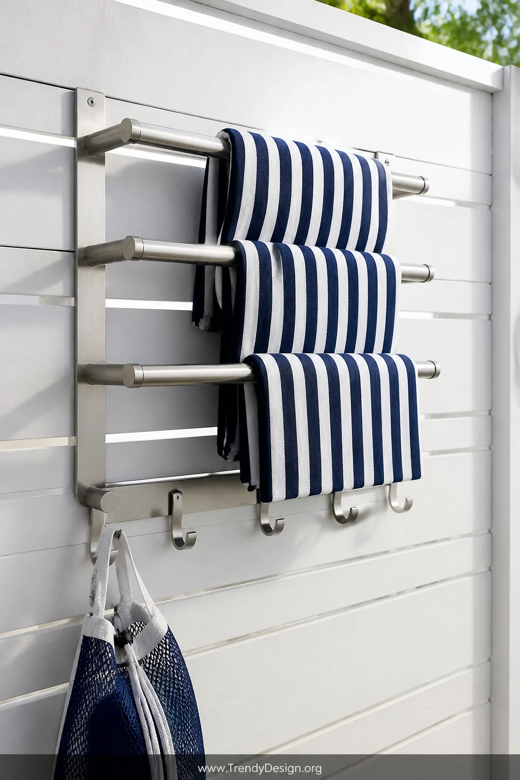 A close-up of a brushed stainless steel wall-mounted towel bar with three horizontal rails and matching hooks below, mounted 