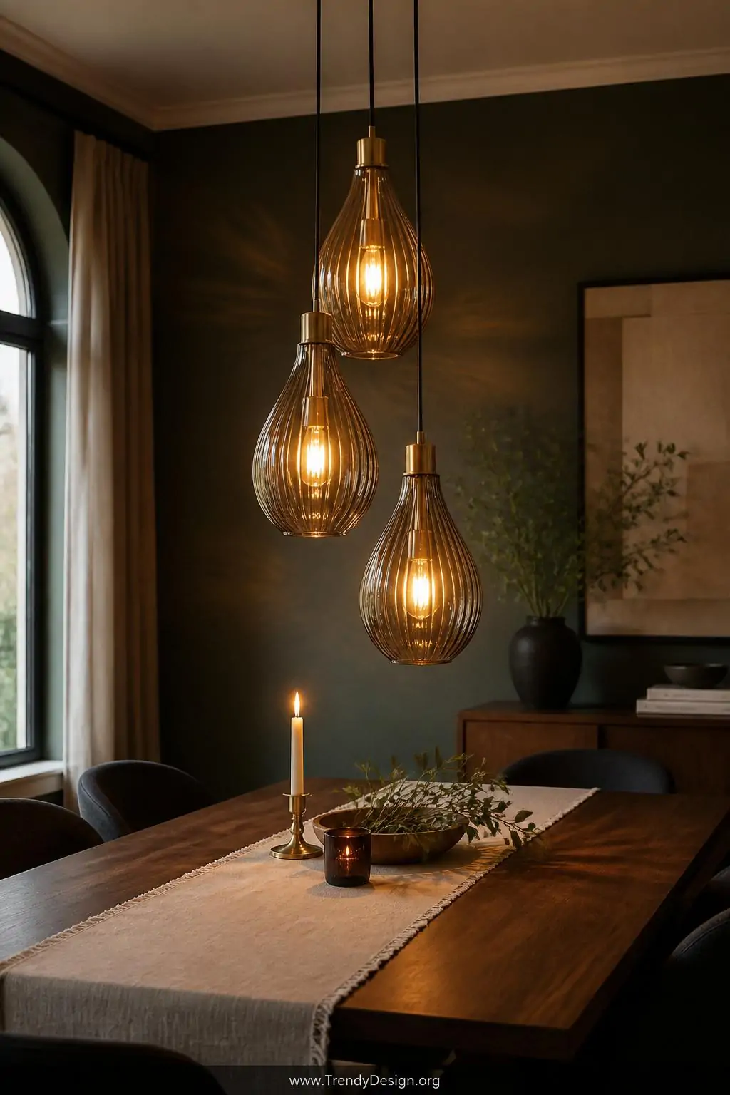Medium shot of three smoked amber glass teardrop pendants suspended at staggered heights over a rectangular dark walnut dinin