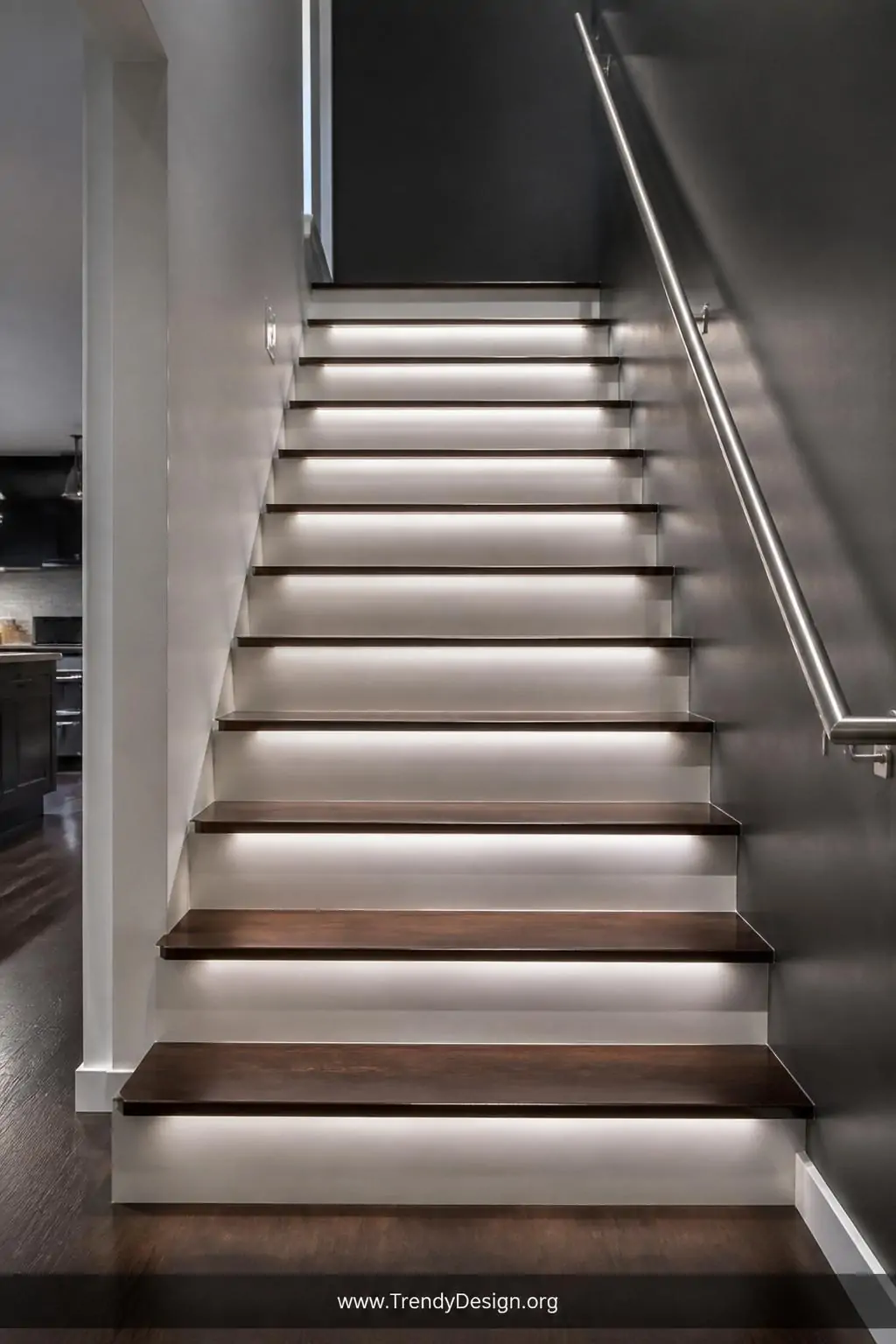 Medium shot looking up a sleek modern staircase with dark walnut treads and white risers, cool neutral white rope lights runn