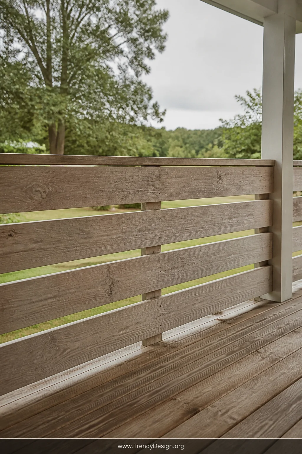 Medium shot of a farmhouse porch railing built from horizontal cedar boards with a light natural wood wash finish, evenly spa