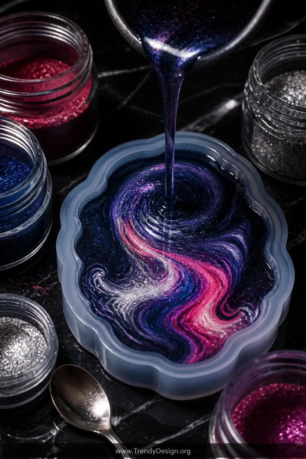 A dramatic closeup of a dark obsidian resin charm mid-pour inside a glossy mold, swirling layers of deep navy, hot pink, and 
