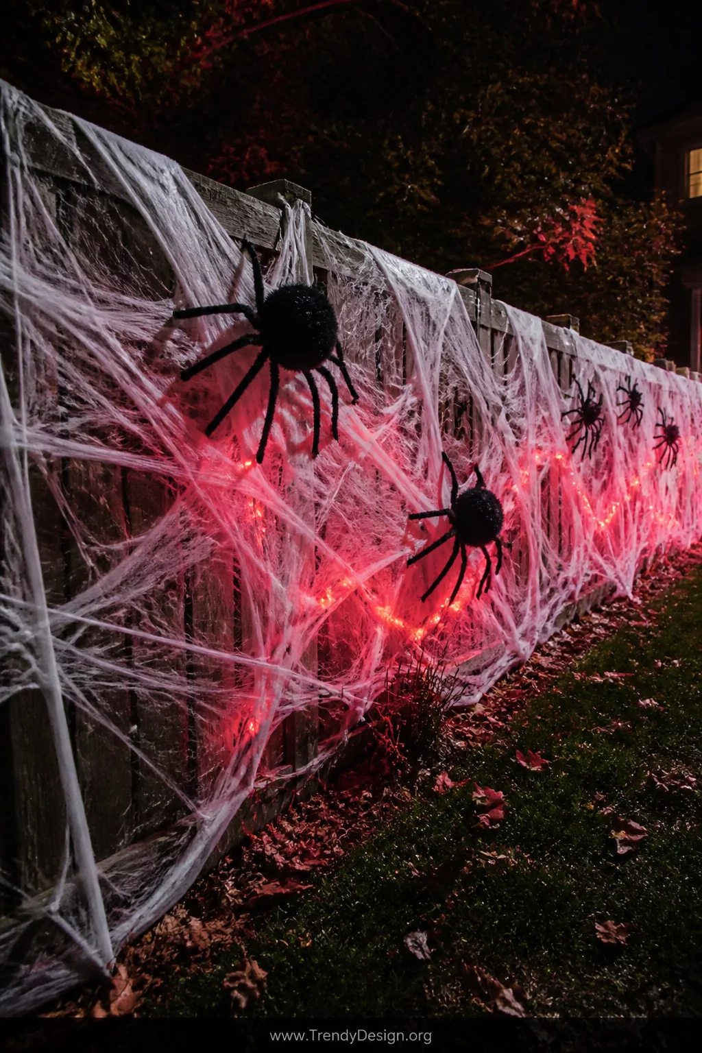 Medium shot of a suburban wooden fence completely overtaken by loosely layered stretchy white spider webbing, large handmade 