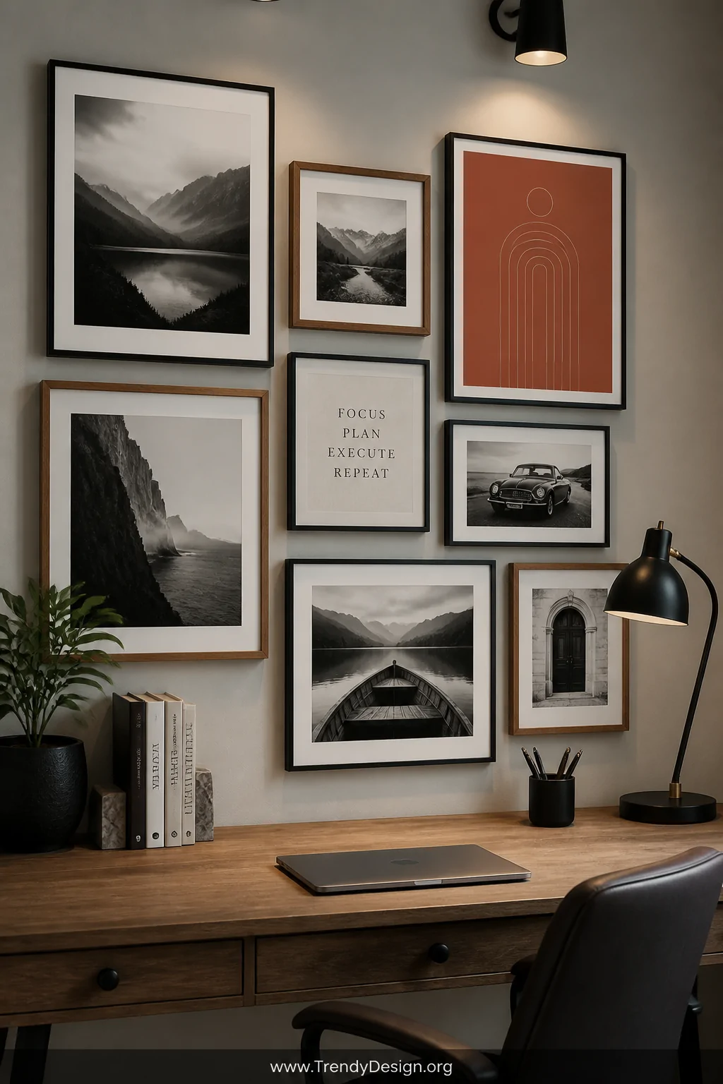 Medium wall shot of a carefully curated gallery wall above an office desk, mix of black thin-frame and warm wood-frame art pr