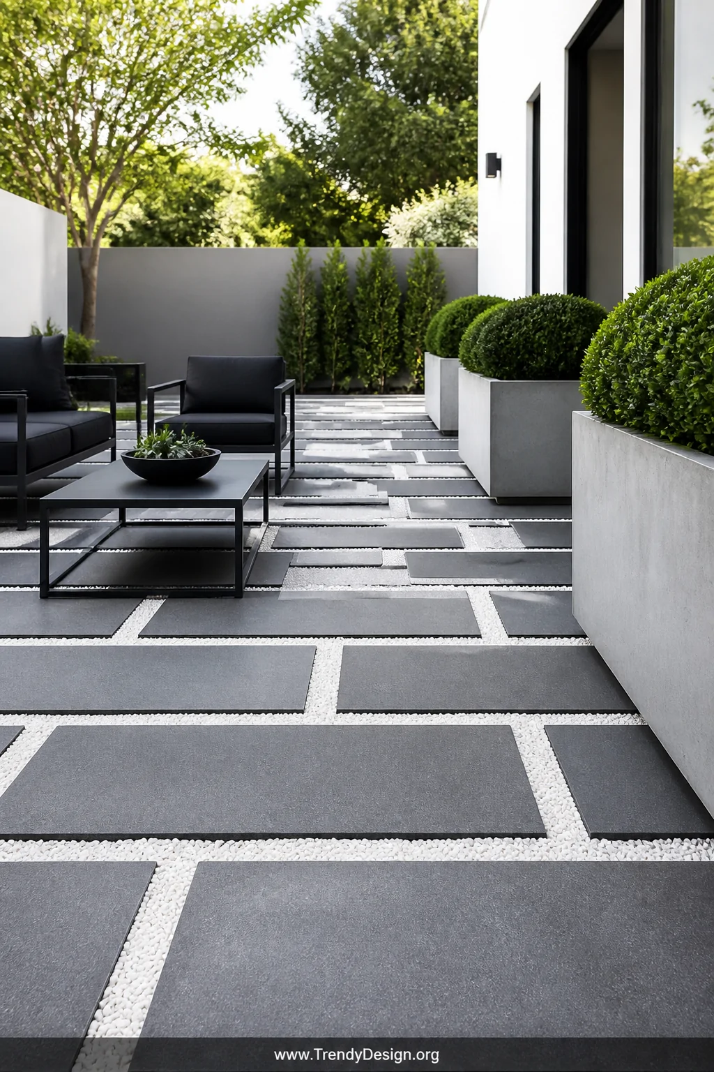 A wide photorealistic shot of a sleek modern geometric patio featuring large-format charcoal gray rectangular concrete pavers