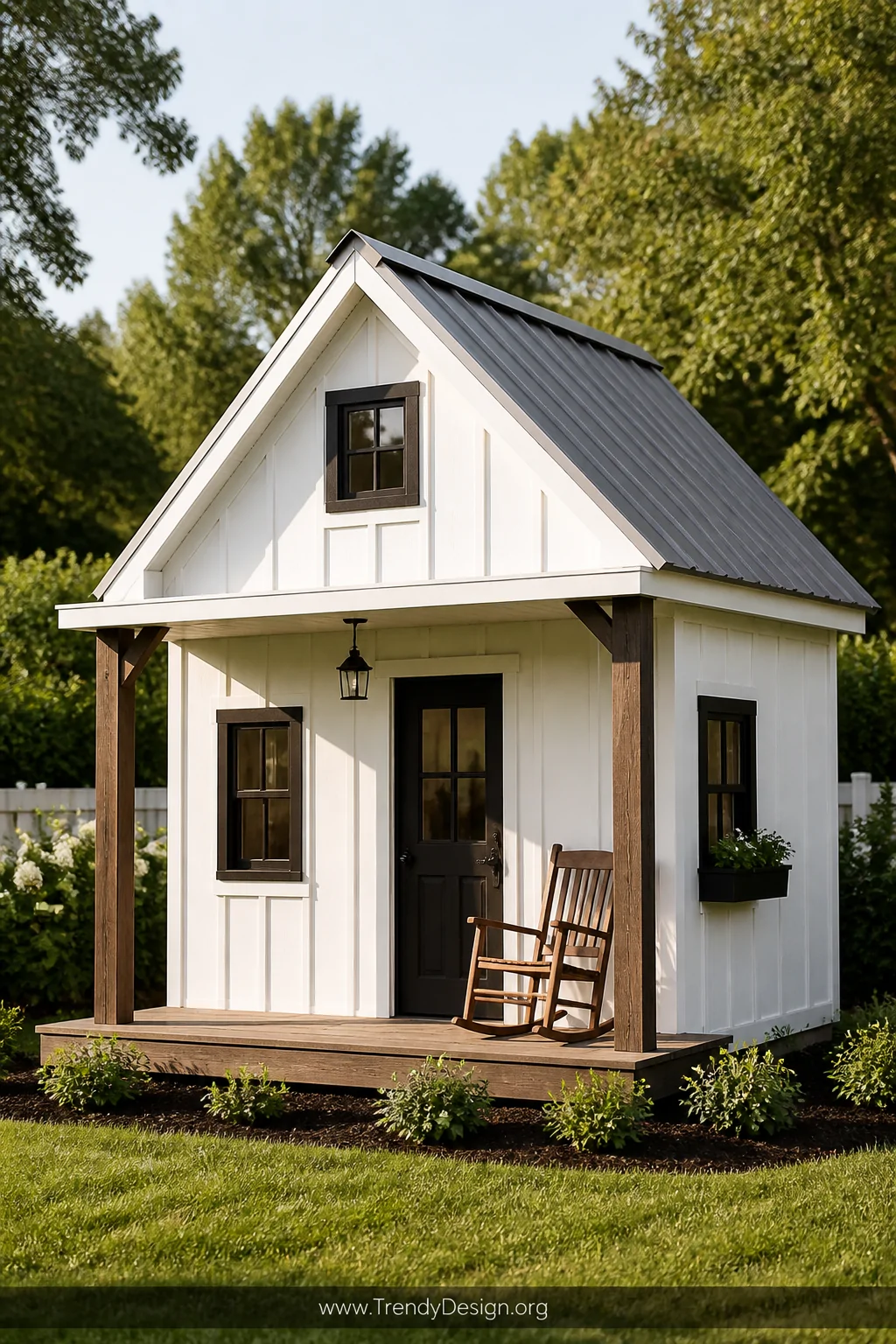 Wide exterior shot of a miniature modern farmhouse playhouse with crisp white vertical board and batten siding, matte black w