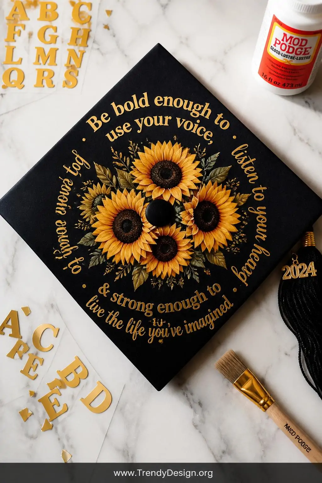 A medium photorealistic flat lay of a graduation cap displayed on a white marble surface, sunflowers clustered at the center 