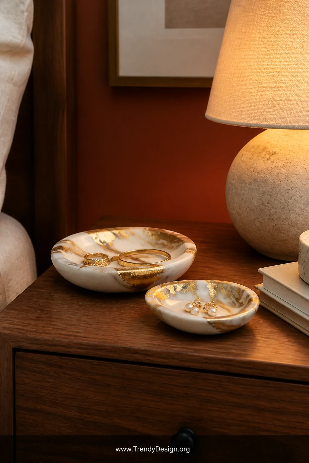Detail closeup shot of a walnut nightstand styled with small polymer clay pinch bowls marbled in ivory and warm gold with gol