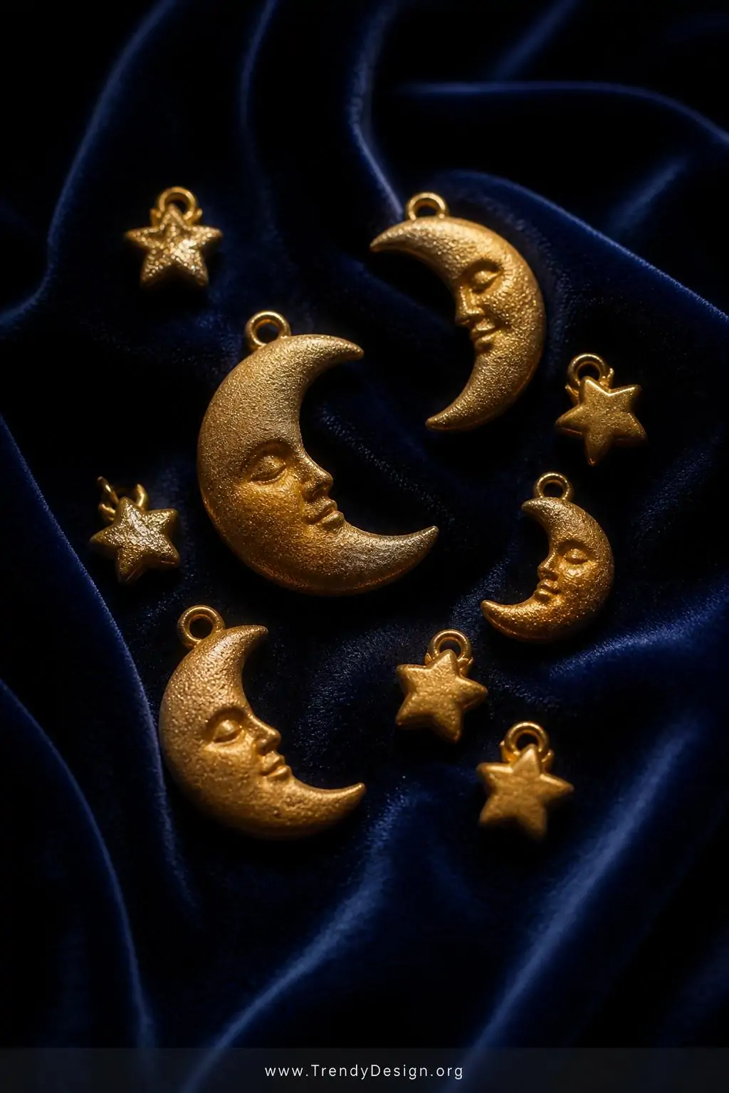 A medium shot of celestial crescent moon and tiny star polymer clay pendants dusted in gold mica powder arranged on deep navy