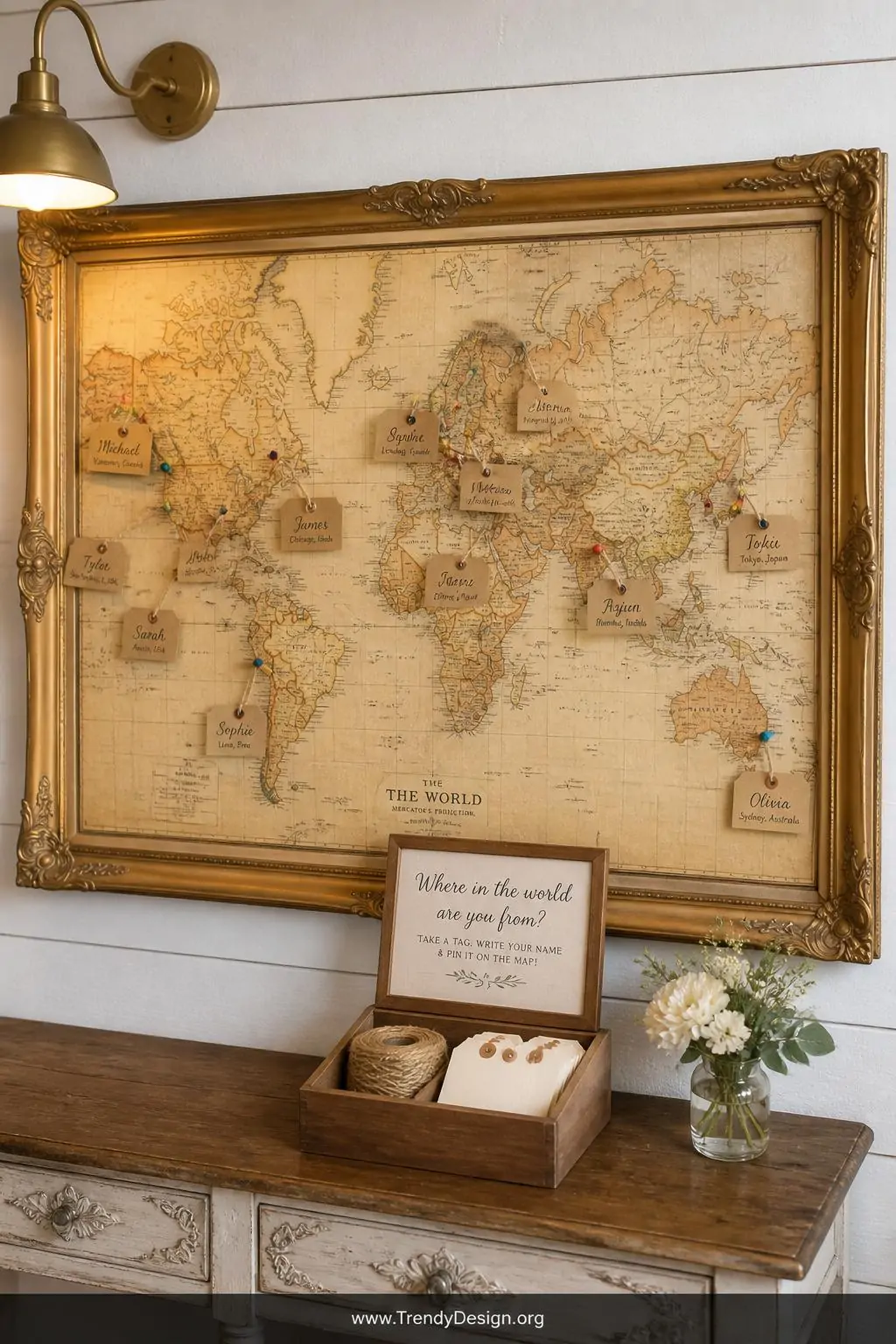 Medium shot of a large ornate gilt-framed vintage world map mounted on a whitewashed shiplap wall, scattered with colorful ma