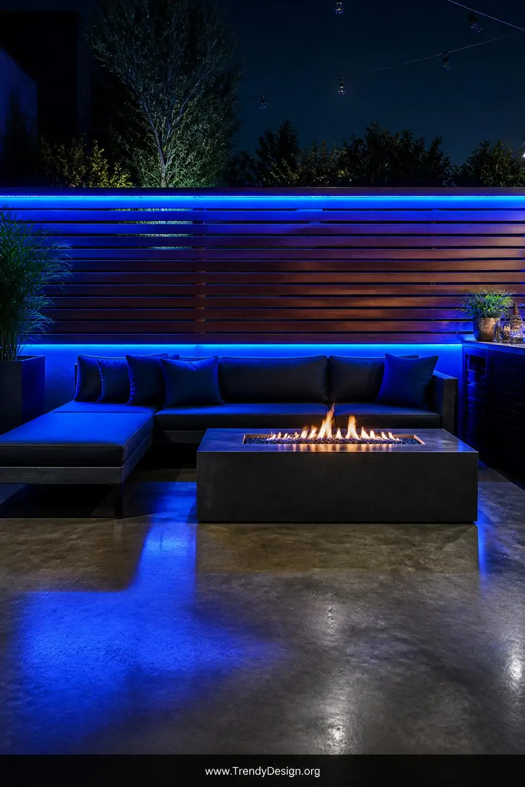 Wide shot of a modern horizontal cedar slat fence with vibrant soft blue LED strip lights running along the bottom and top ra