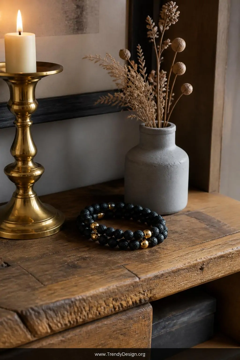 Medium shot of a sophisticated styled surface featuring a lava bead bracelet with gleaming gold accent beads coiled beside a 