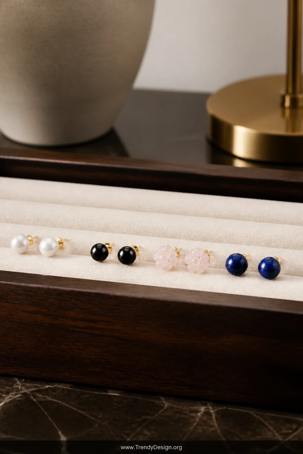 An intimate closeup detail shot on a polished dark walnut jewelry tray lined with cream velvet, four pairs of delicate beaded