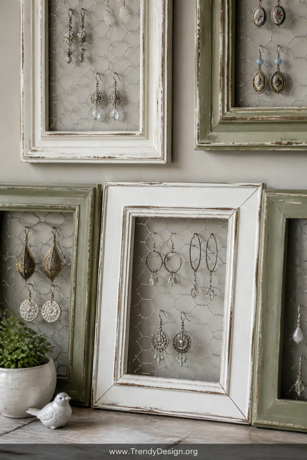 Detail closeup of multiple distressed vintage picture frames with chicken wire stretched across their backs, earrings hanging