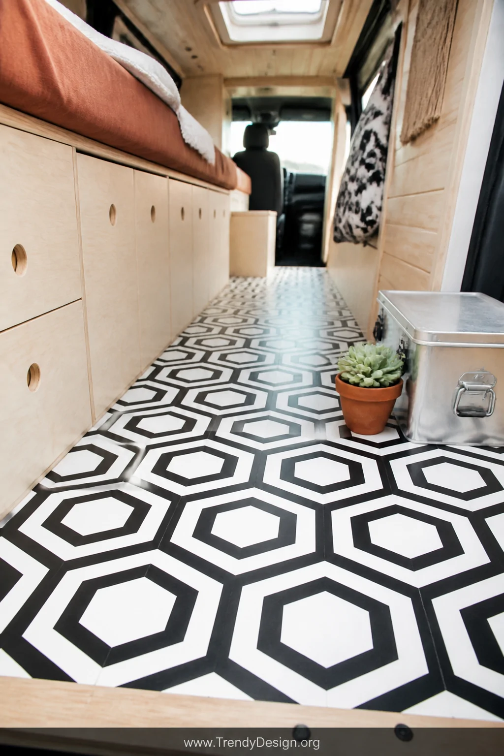 A medium-shot photorealistic van interior floor featuring bold black-and-white geometric peel-and-stick vinyl tiles in a hexa