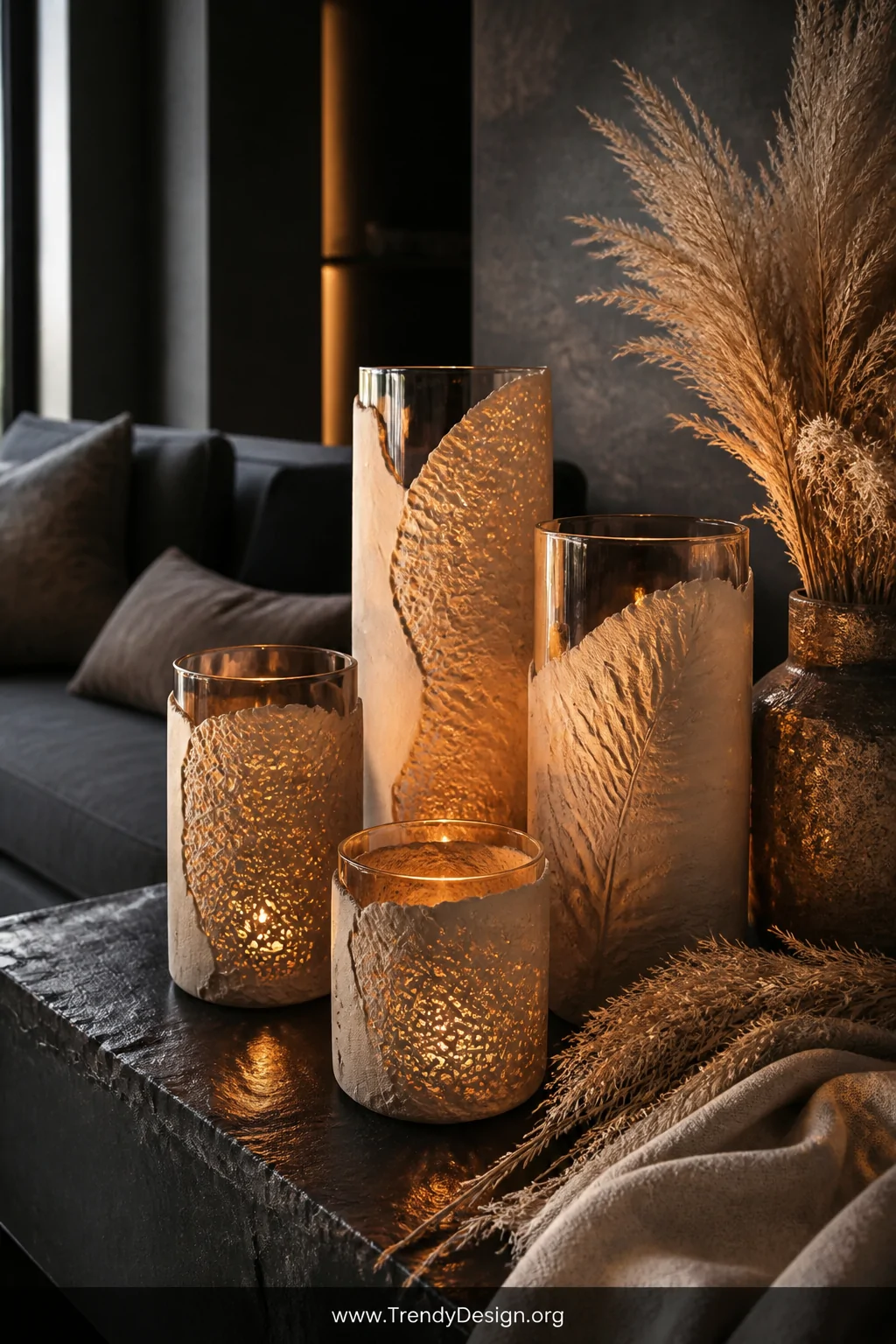 Medium shot of a moody living room vignette featuring a cluster of tall and short glass cylinder candle holders wrapped in te