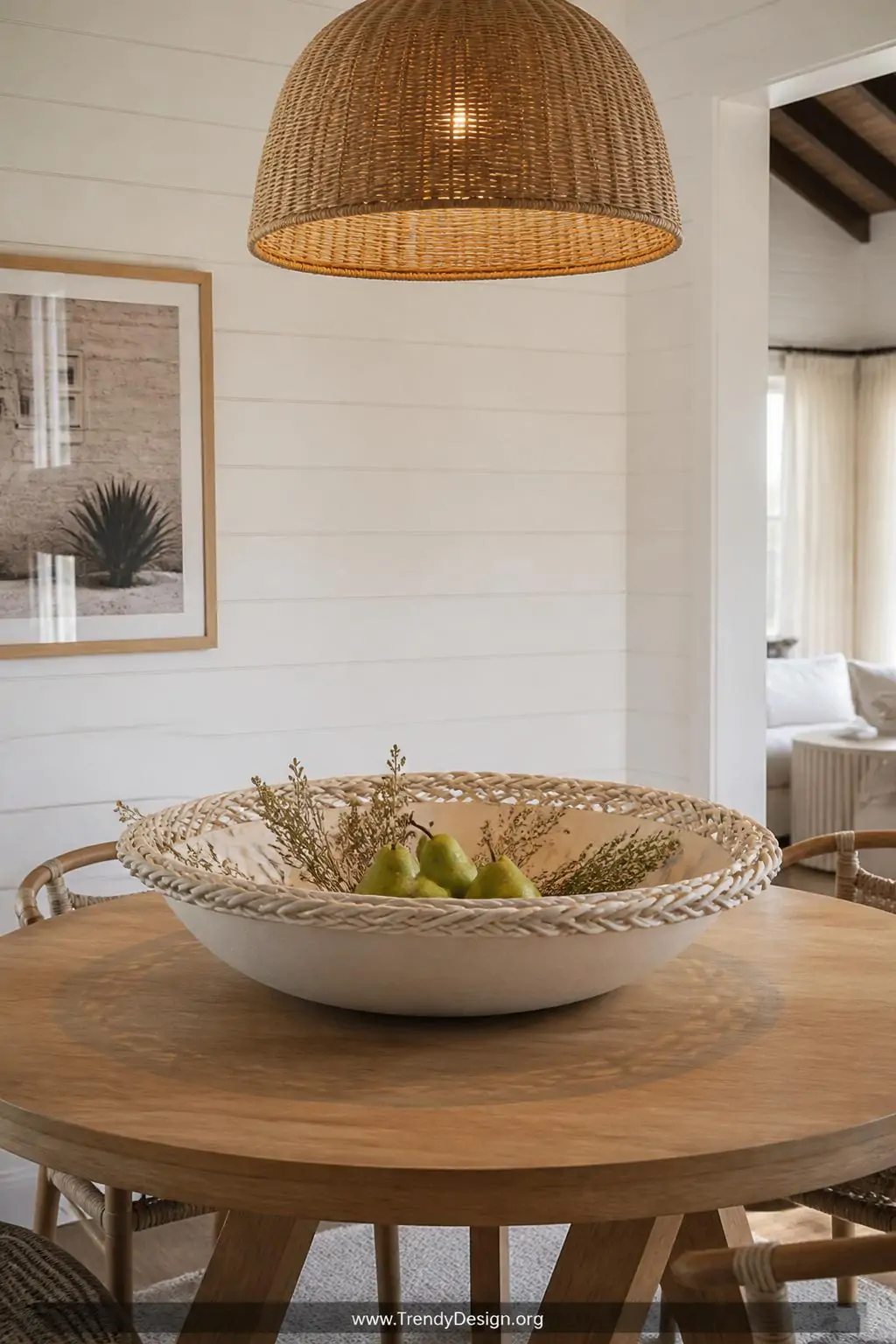 A wide shot of a large cream matte braided rim statement bowl styled as a centerpiece on a round timber dining table in a bri