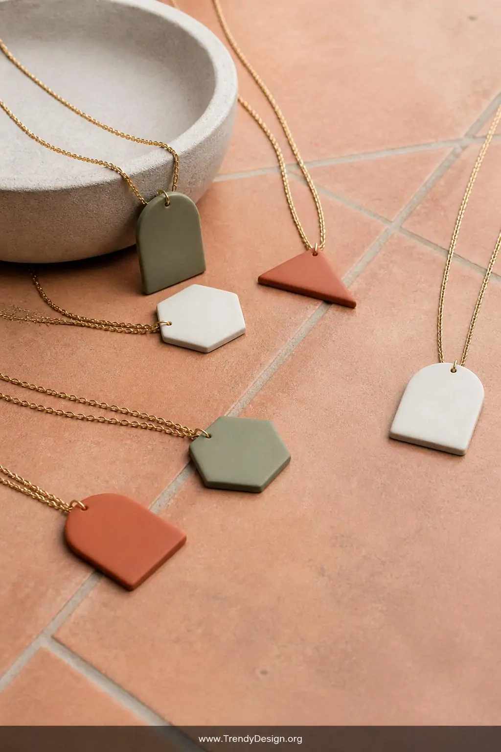 A wide shot of a minimalist styled flat lay on warm terracotta tiles, featuring geometric arch triangle and hexagon polymer c
