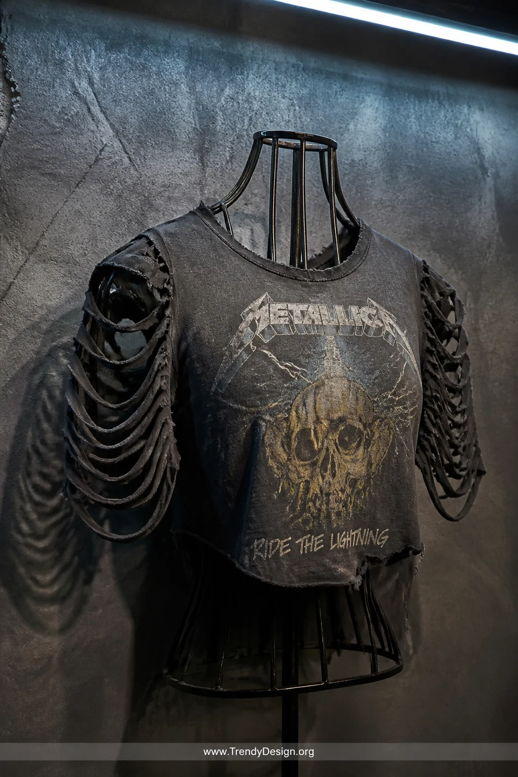A medium closeup shot of a vintage band tee mounted on a dark metal display form against a distressed charcoal concrete wall 