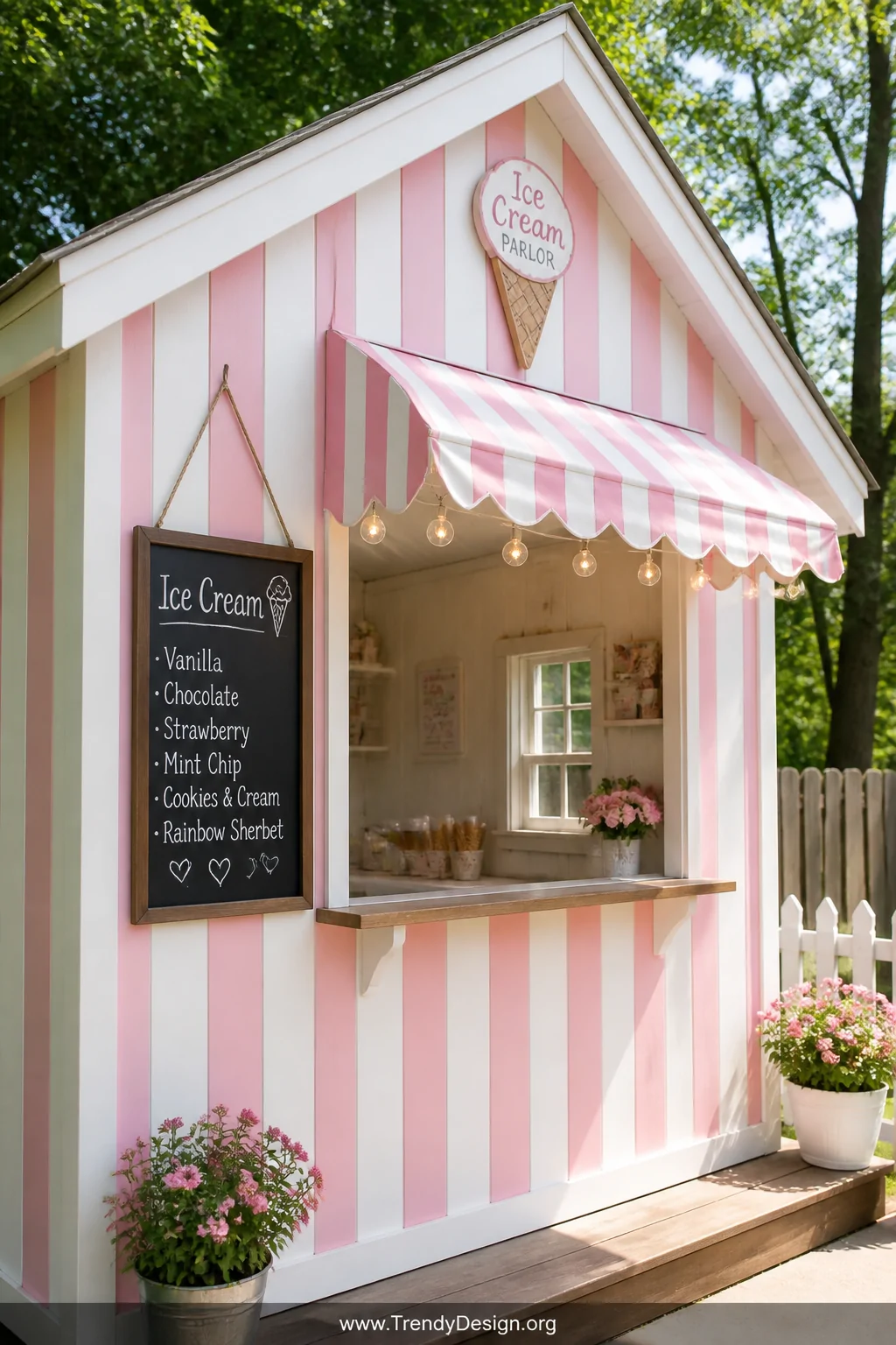 Medium exterior shot of a vintage ice cream parlor playhouse with alternating pink and white vertical painted stripes, a chee