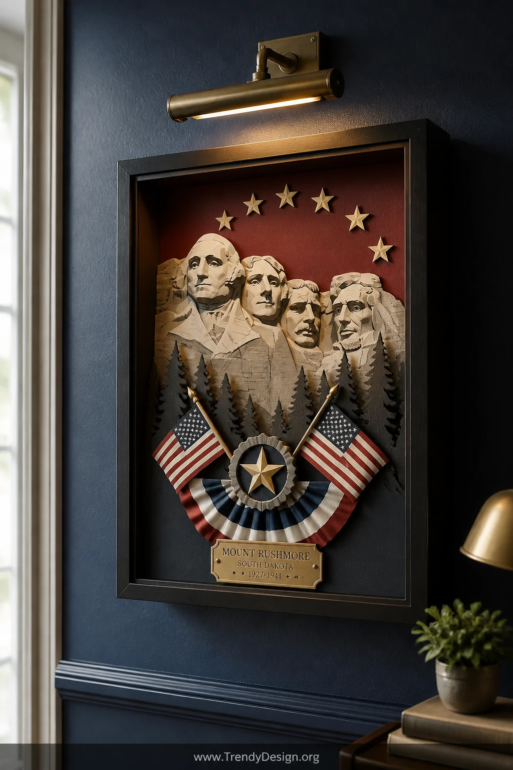 A medium shot of a deep shadow box frame mounted on a navy blue accent wall, displaying a layered Mount Rushmore silhouette b