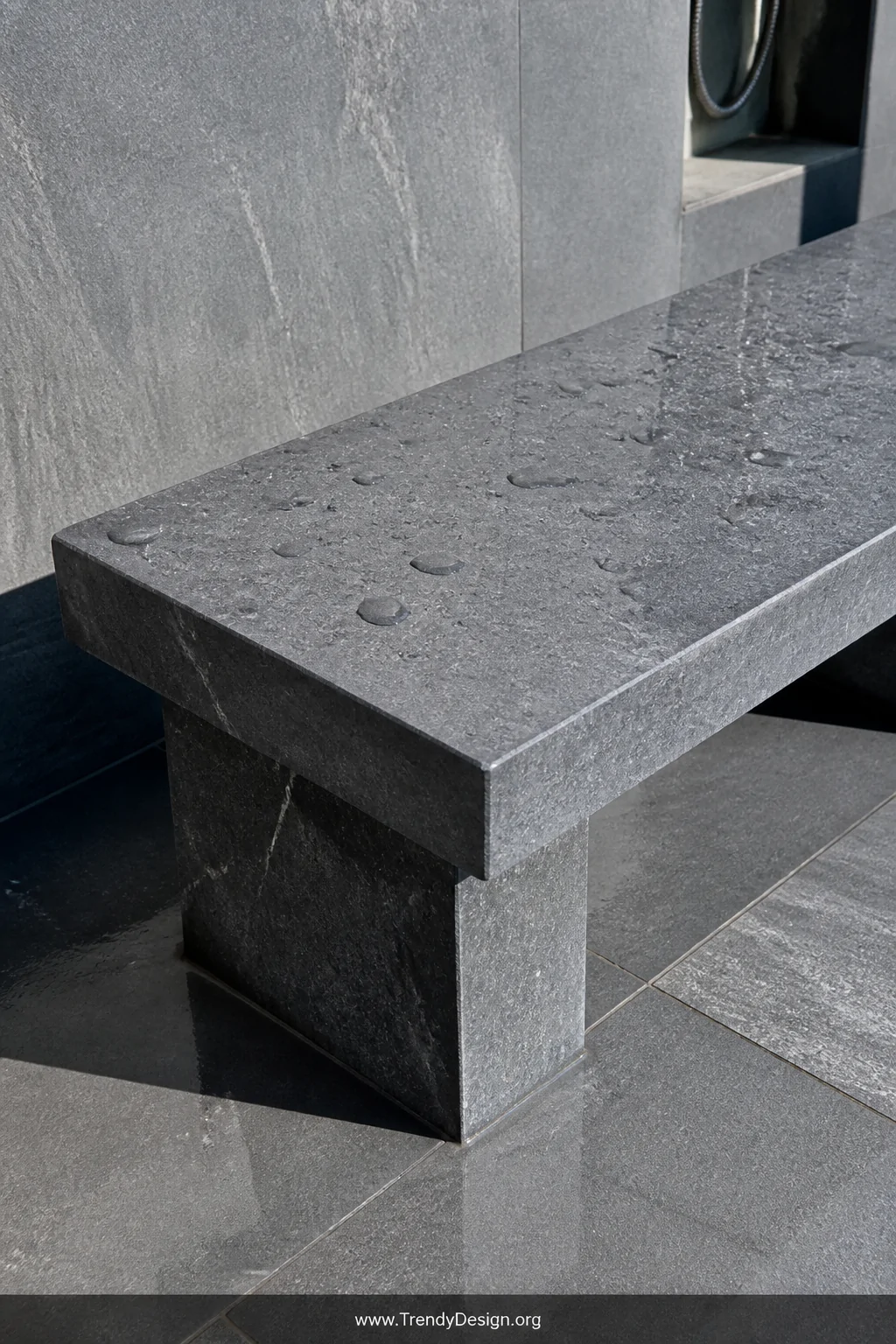 Closeup detail shot of a rectangular bluestone slab outdoor shower bench resting on two solid stone block legs, the honed mat