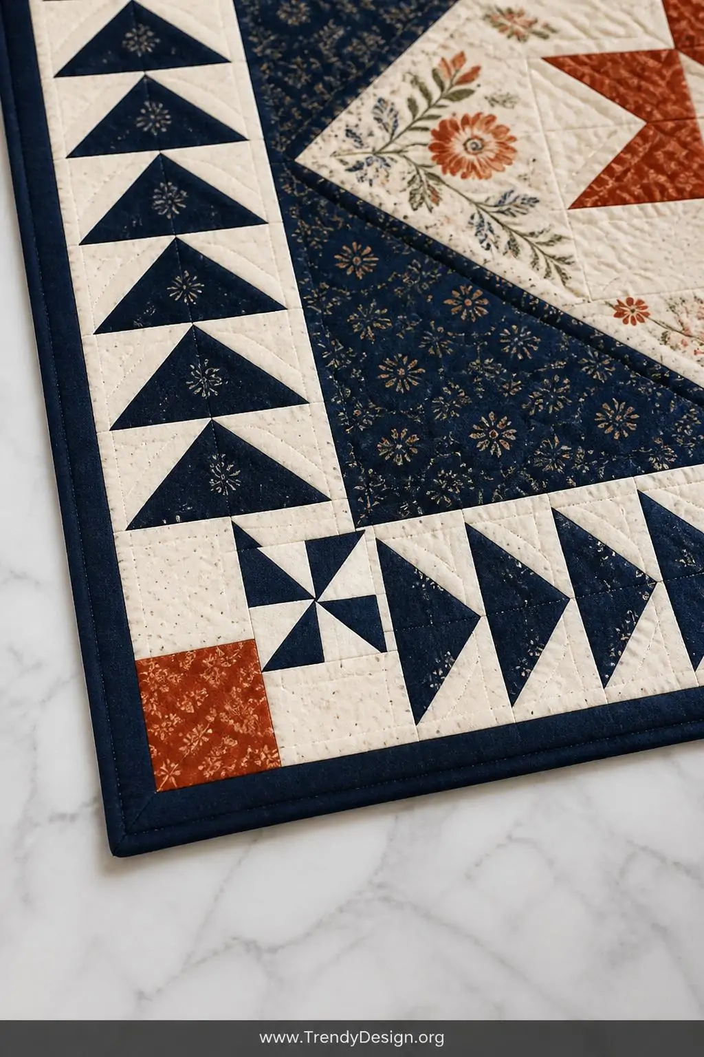 Closeup shot of a quilt corner resting on a marble surface showing a flying geese border with a perfectly placed cornerstone 