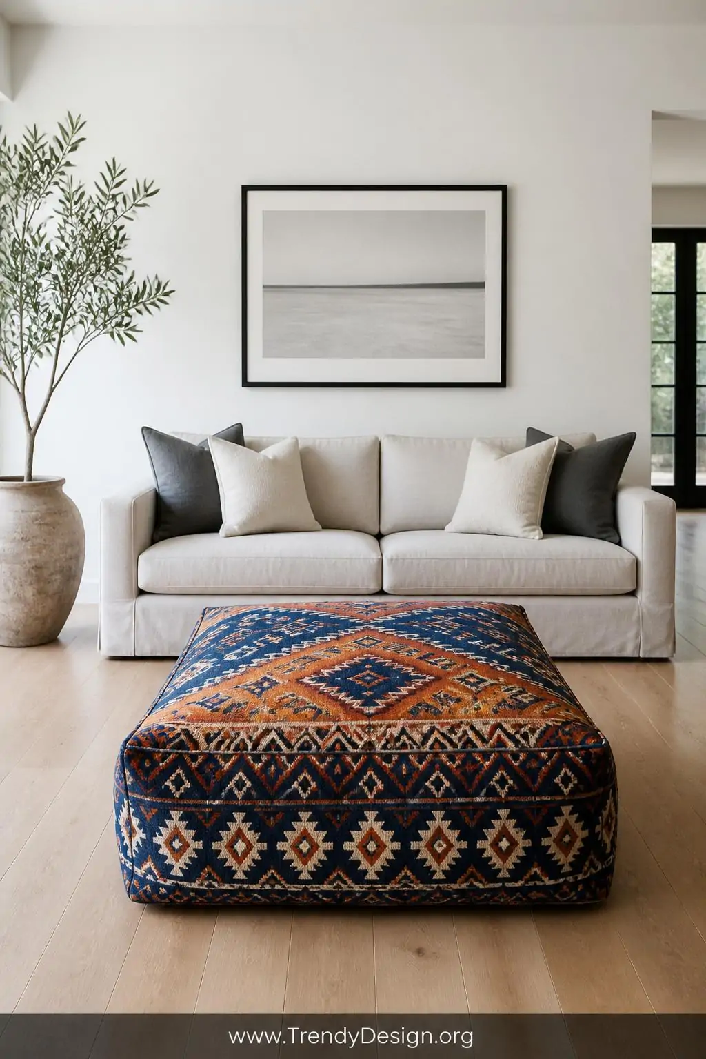 A wide-shot photorealistic interior of a minimalist living room where a bold tribal geometric printed poof in navy cobalt and