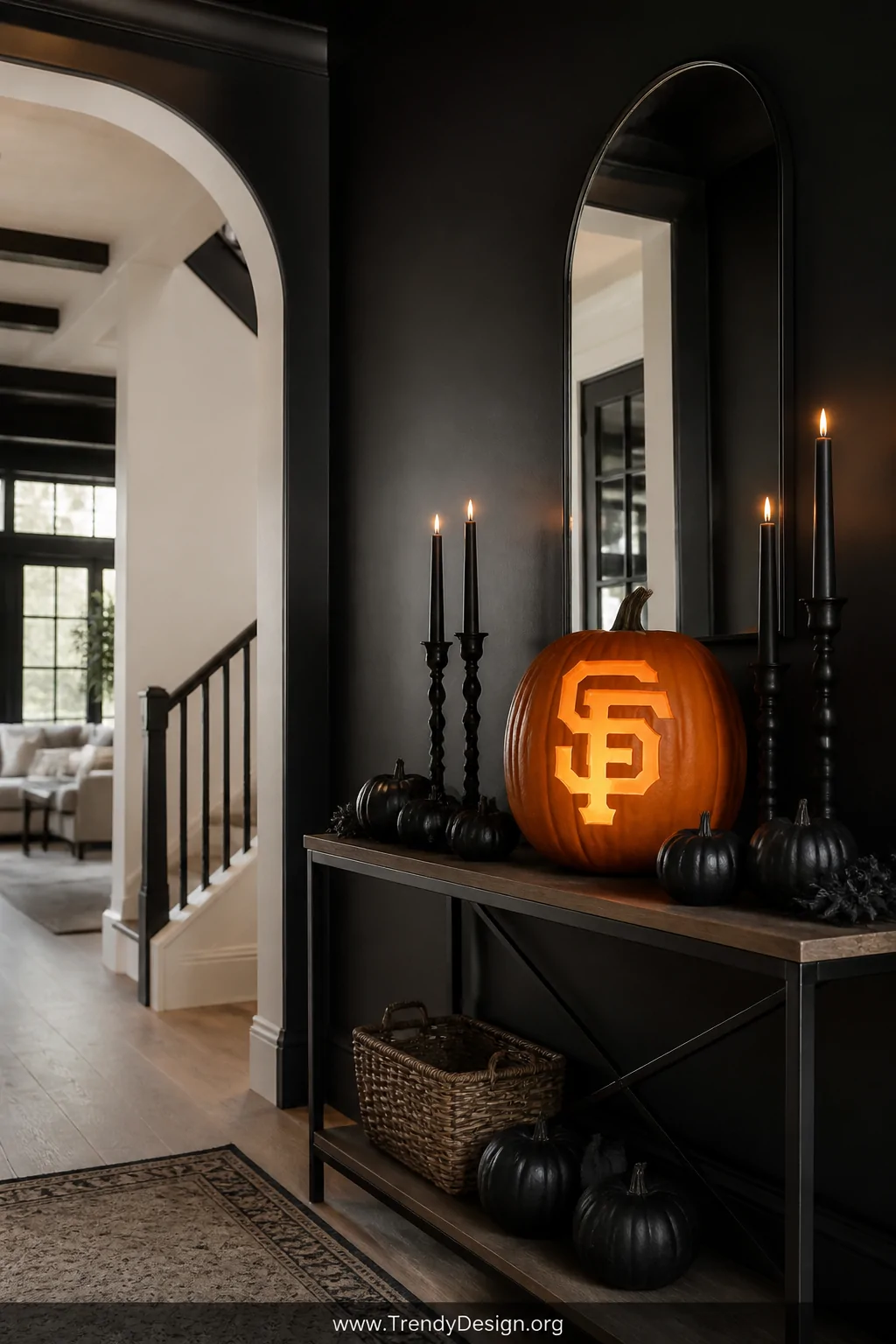 A wide interior shot of a Halloween-decorated entryway with black painted walls and a console table holding a single large pu