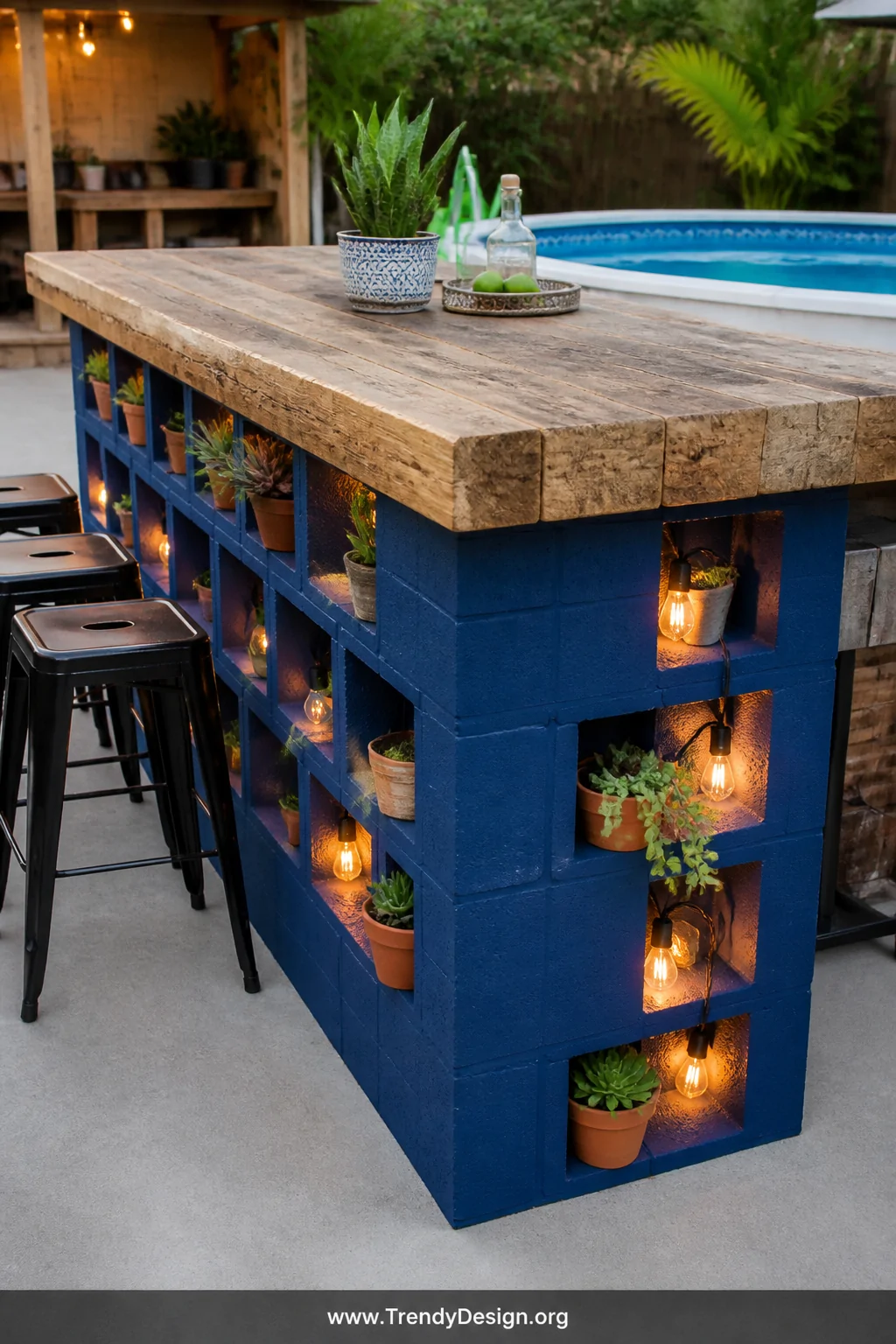 A medium shot of a bold cobalt-blue painted cinder block and thick reclaimed wood plank bar counter positioned on a grey conc