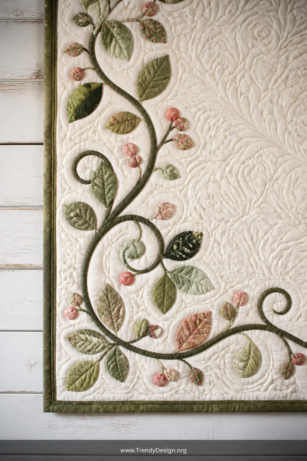 Detail closeup of an elegant curved appliqué vine border on a quilt displayed against a whitewashed shiplap wall, sinuous gre