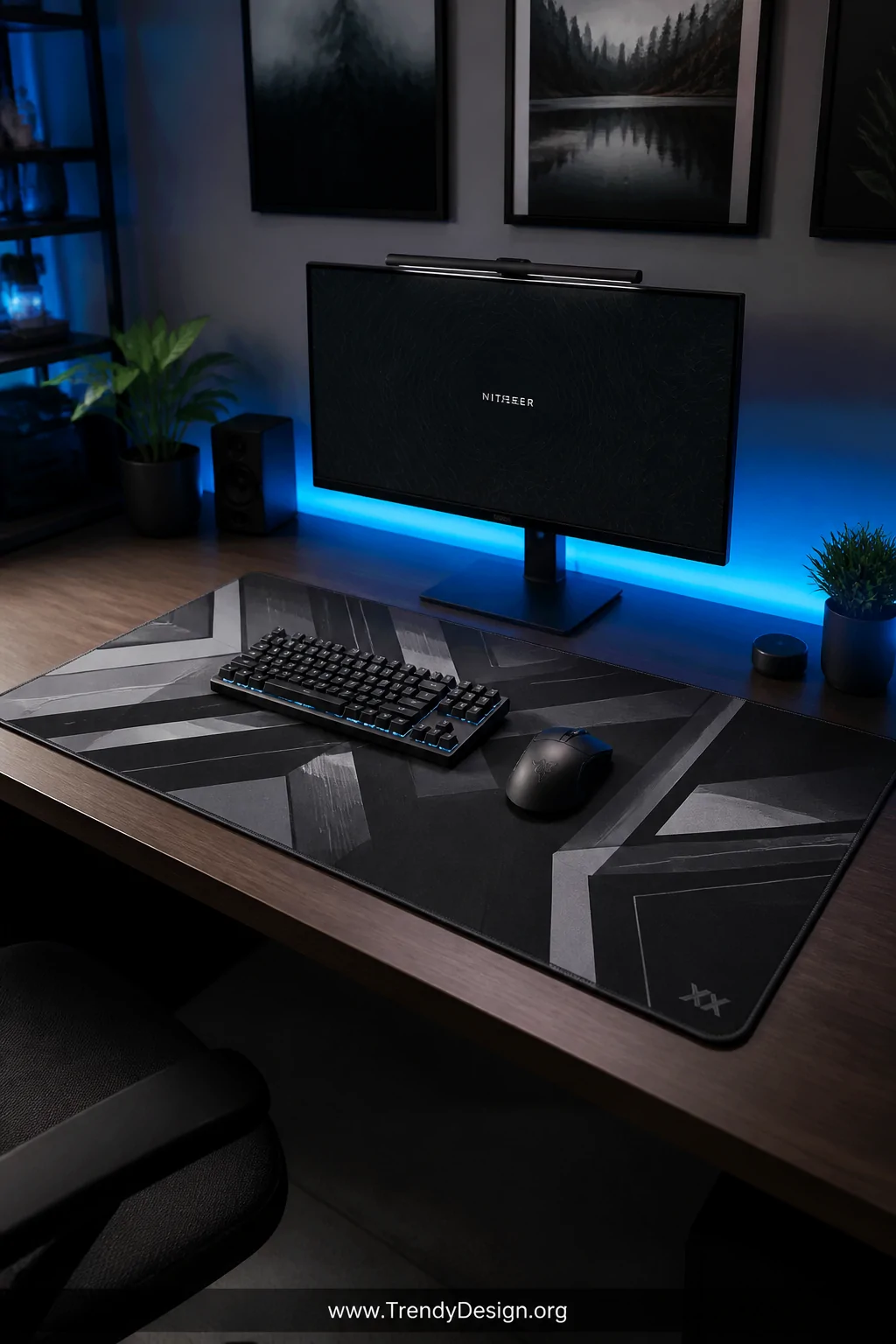 A wide shot of a bold, dynamic home office desk setup featuring a large edge-stitched gaming mousepad with a sharp dark geome