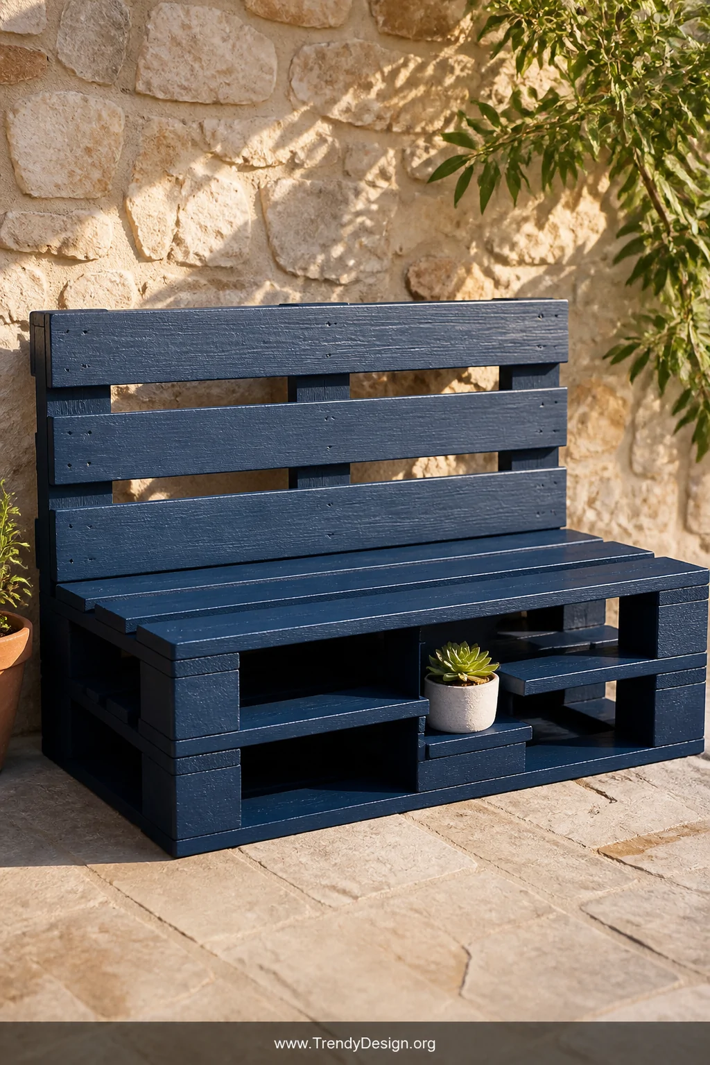 Medium shot of a DIY wooden pallet bench painted in deep navy blue with a smooth outdoor-grade finish, positioned against a b
