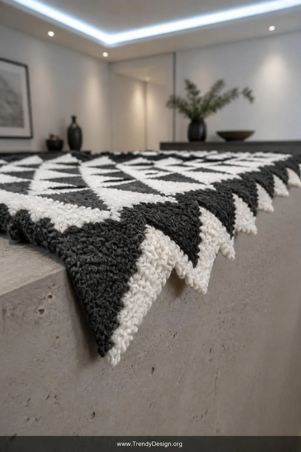 A close-up photorealistic shot of a geometric C2C blanket edge laid flat on a concrete-textured side table in a modern minima