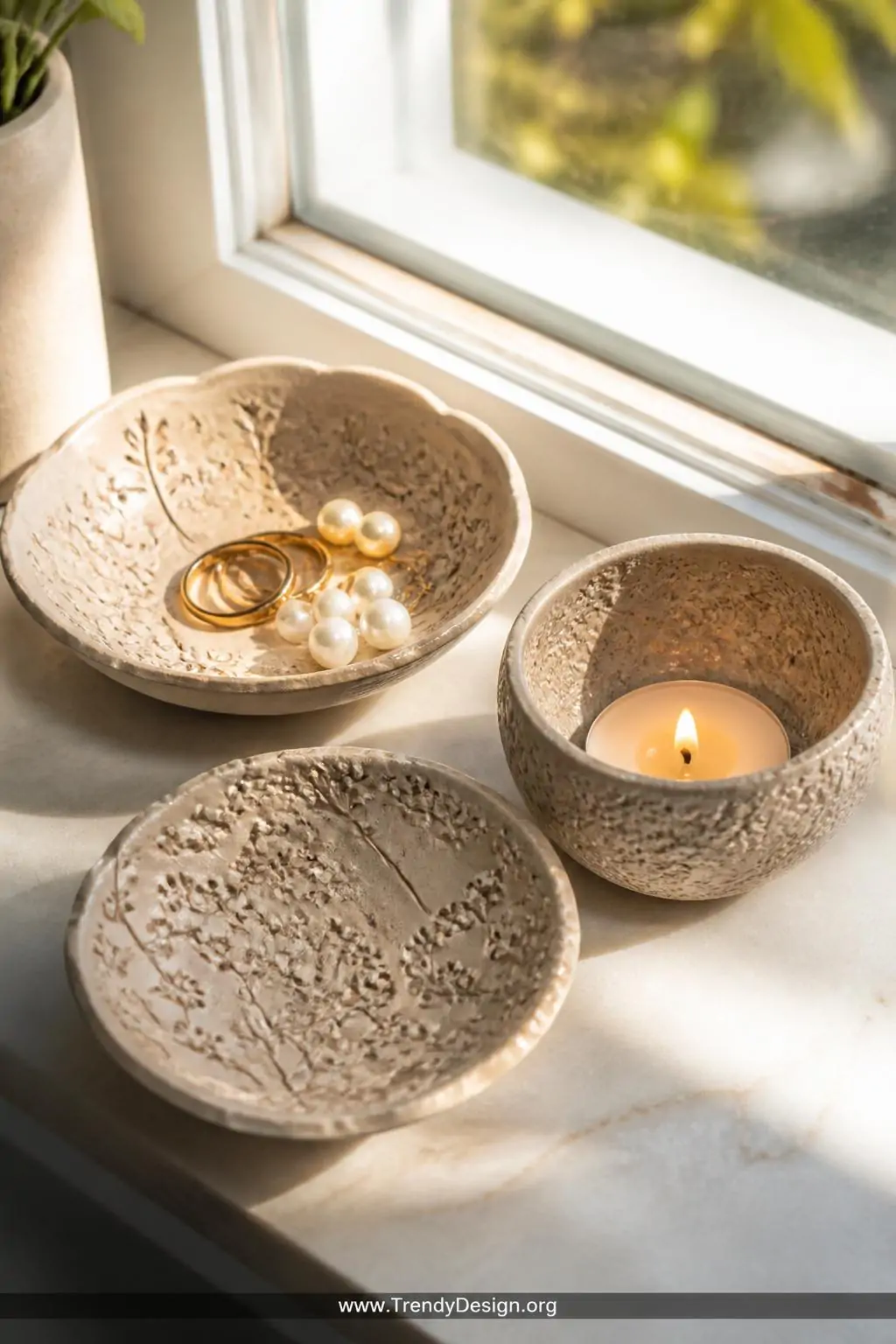 A closeup shot of three small stamped pattern trinket bowls arranged on a sun-drenched windowsill, each bowl covered in intri