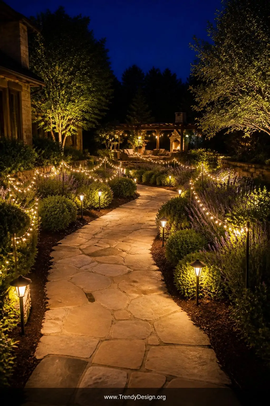 Wide photorealistic shot of a winding garden pathway at night bordered by low string light strands threaded through lush lave