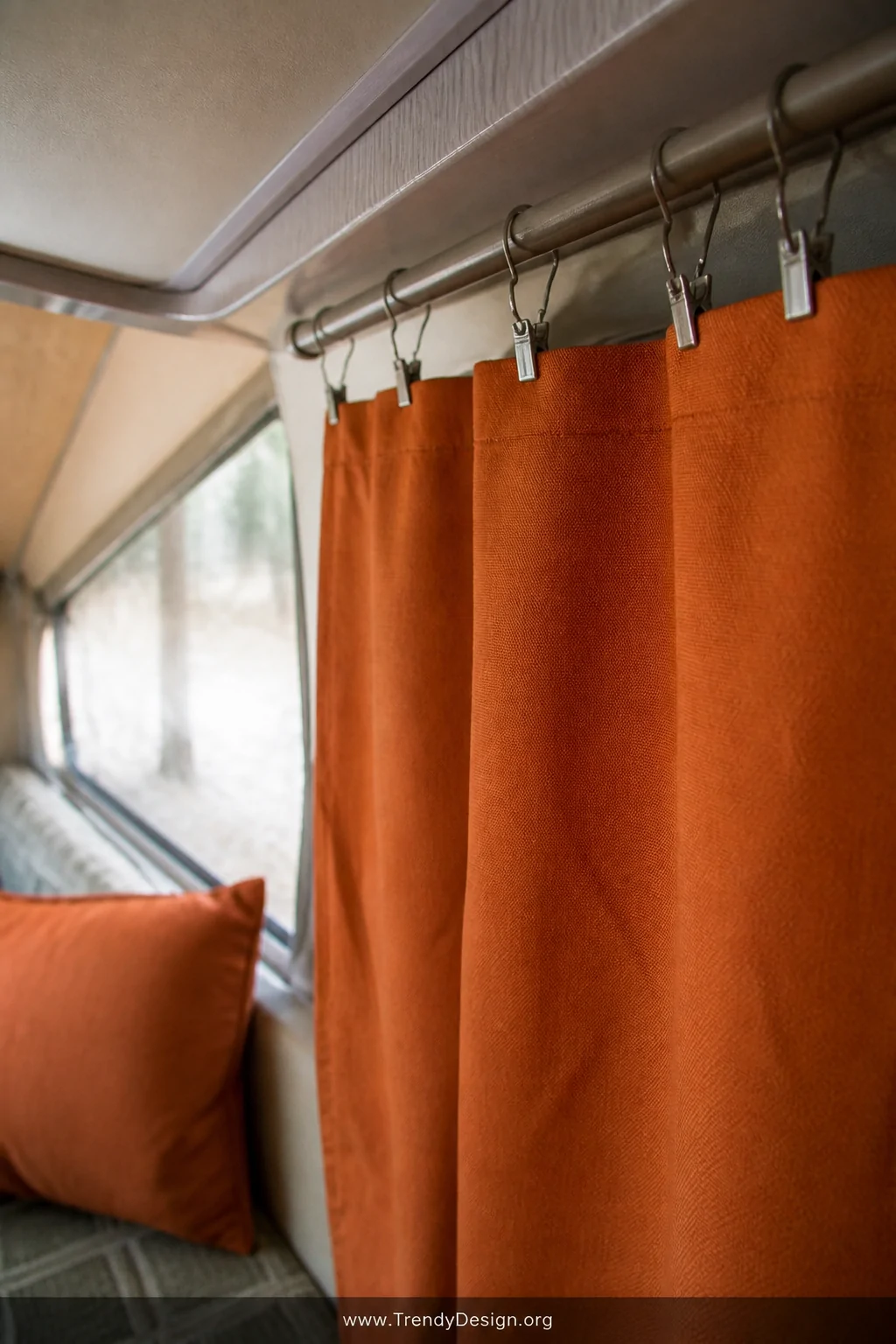 Closeup detail shot of a handmade pop-up camper curtain panel in vibrant rust orange outdoor canvas fabric, raw edges finishe