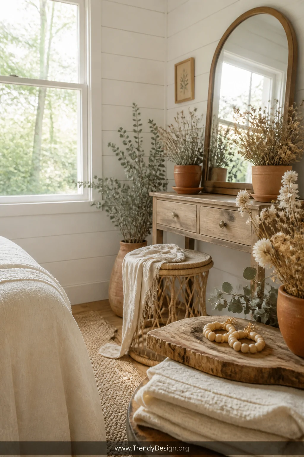 A wide shot of a bright cottagecore-inspired bedroom corner with whitewashed shiplap walls, a rattan vanity stool draped in a