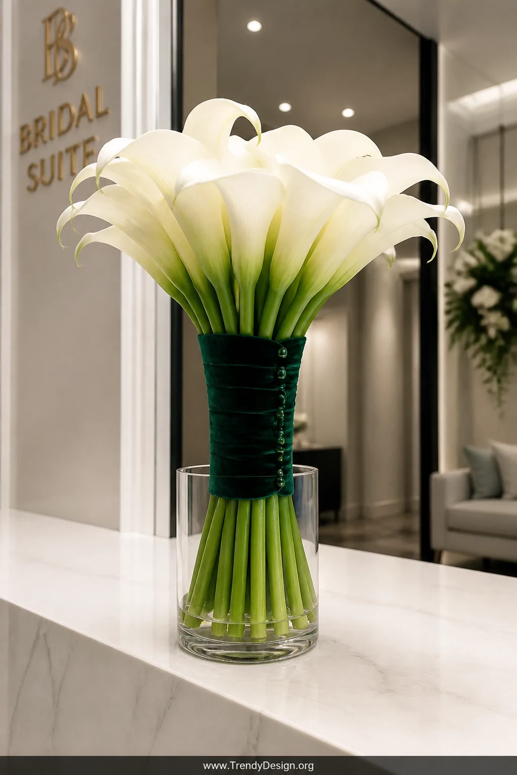 An elegantly hand-tied calla lily bouquet with long stems fanned and gathered, wrapped in deep emerald green velvet ribbon wi